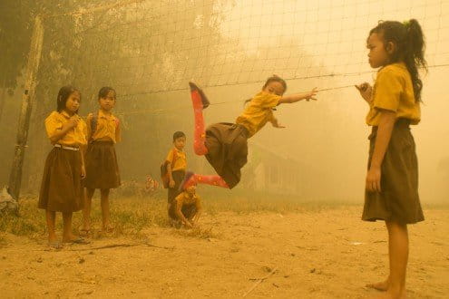 Children enjoy playing without wearing any protection at the playground while the air is engulfed with thick haze from the forest fires at Sei Ahass village, Kapuas district in Central Kalimantan province on Borneo island, Indonesia. These fires are a threat to the health of millions. Smoke from landscape fires kills an estimated 110,000 people every year across Southeast Asia, mostly as a result of heart and lung problems, and weakening newborn babies.