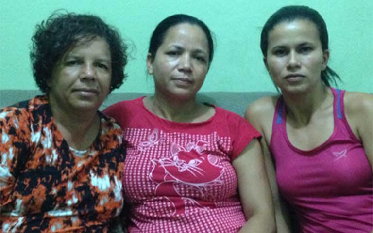 Survivor Neuza da Silva Santos sits between two of her colleagues from an agricultural cooperative that produces a pepper jelly. They all lived in Bento Rodrigues, the town destroyed by the toxic mud flow, and have re-started their cooperative with support from Samarco, the company that owned the dam. The women originally started their coop in 2002 as an economic alternative to mining. Marlene Iaquil Serra sits on the left, and Keila Vardeli Oialho on the right. Photo by Zoe Zullivan