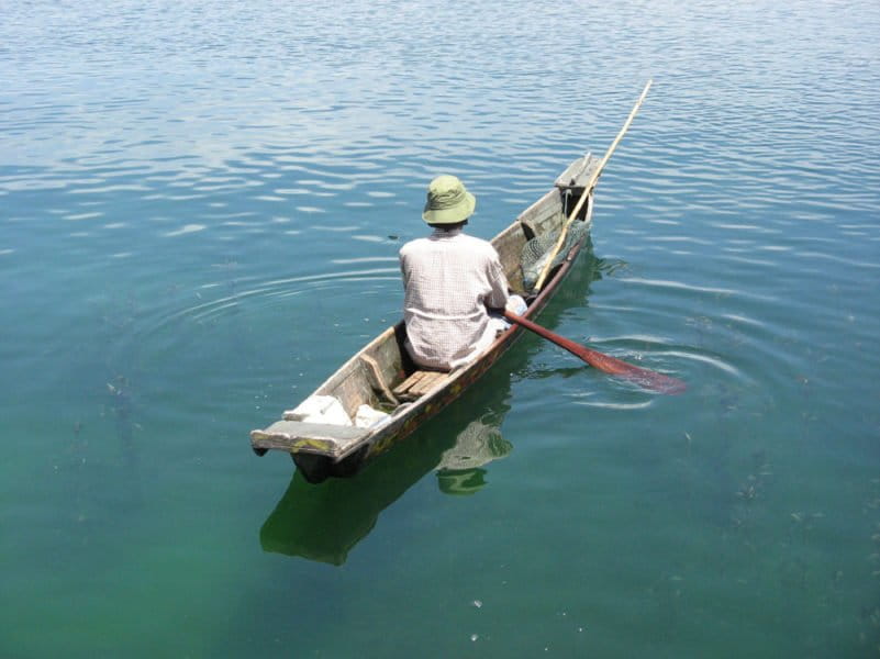 A fish farmer uses a small canoe to check his floating cages in Indonesia's Lake Toba, in North Sumatra province. Photo by isawasi/Flickr