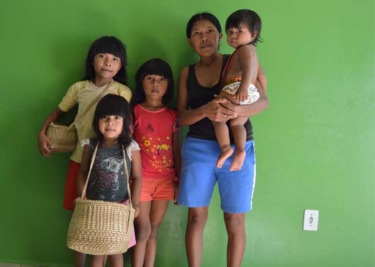 Tamawaerw Paracanã and her family. Besides the small income she earns from the crafts she makes and sells, their only income is the 200 Reals (approximately US $59) per month provided by the Bolsa Familia government subsidy program. Tamawaerw’s husband has been unable to find work in the city of Altamira where the family was relocated when the dam was built. Photo by Zoe Sullivan