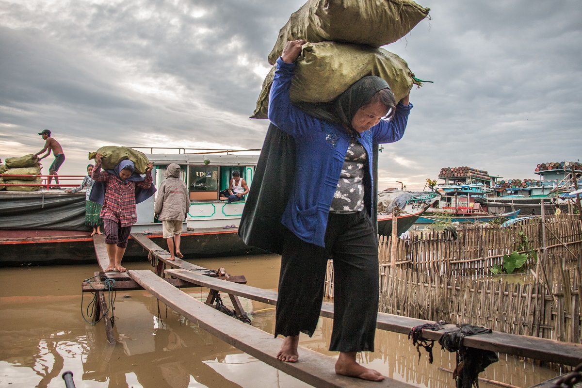 Women unload charcoal from a boat in the town of Bhamo, along the Irrawaddy River. Photo by Nathan Siegel for Mongabay.