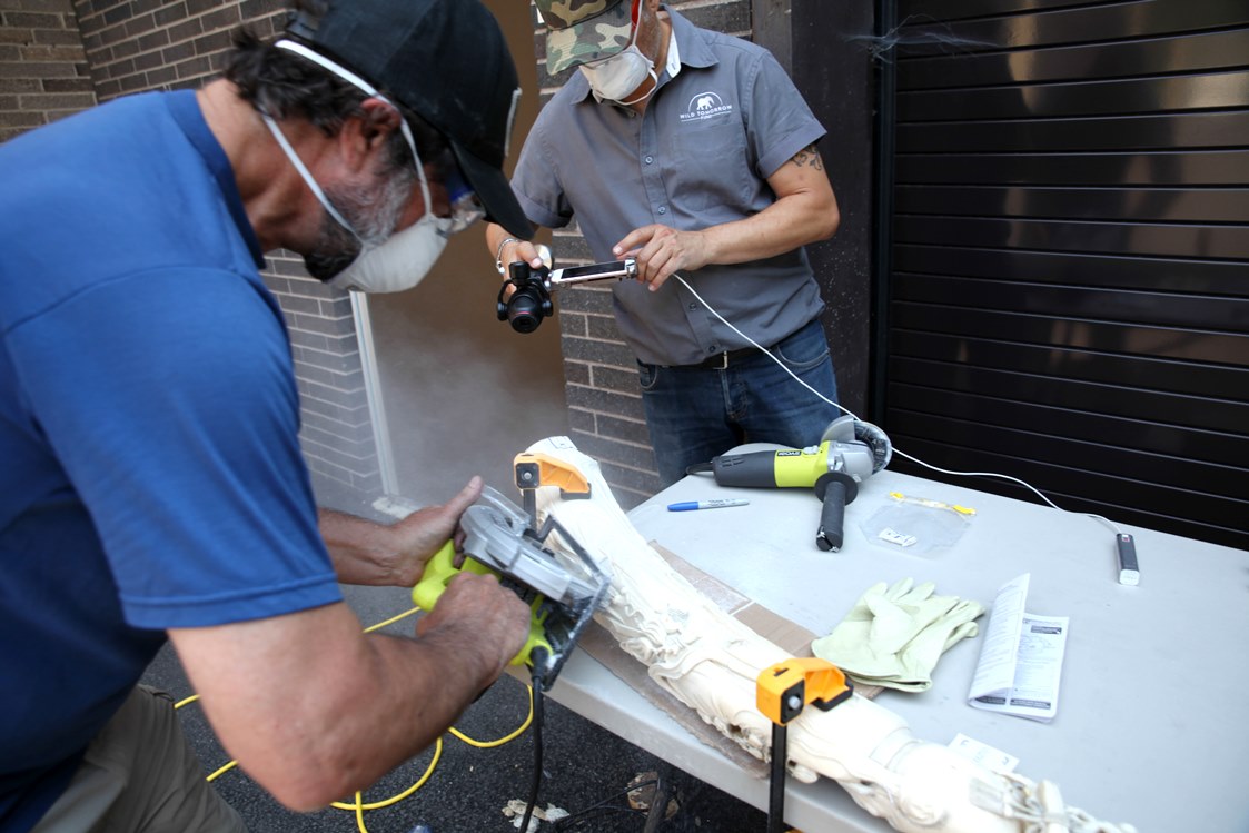 Sam Wasser (left) cuts an ivory sample from a carved tusk while John Steward of Wild Tomorrow Fund documents the process. 