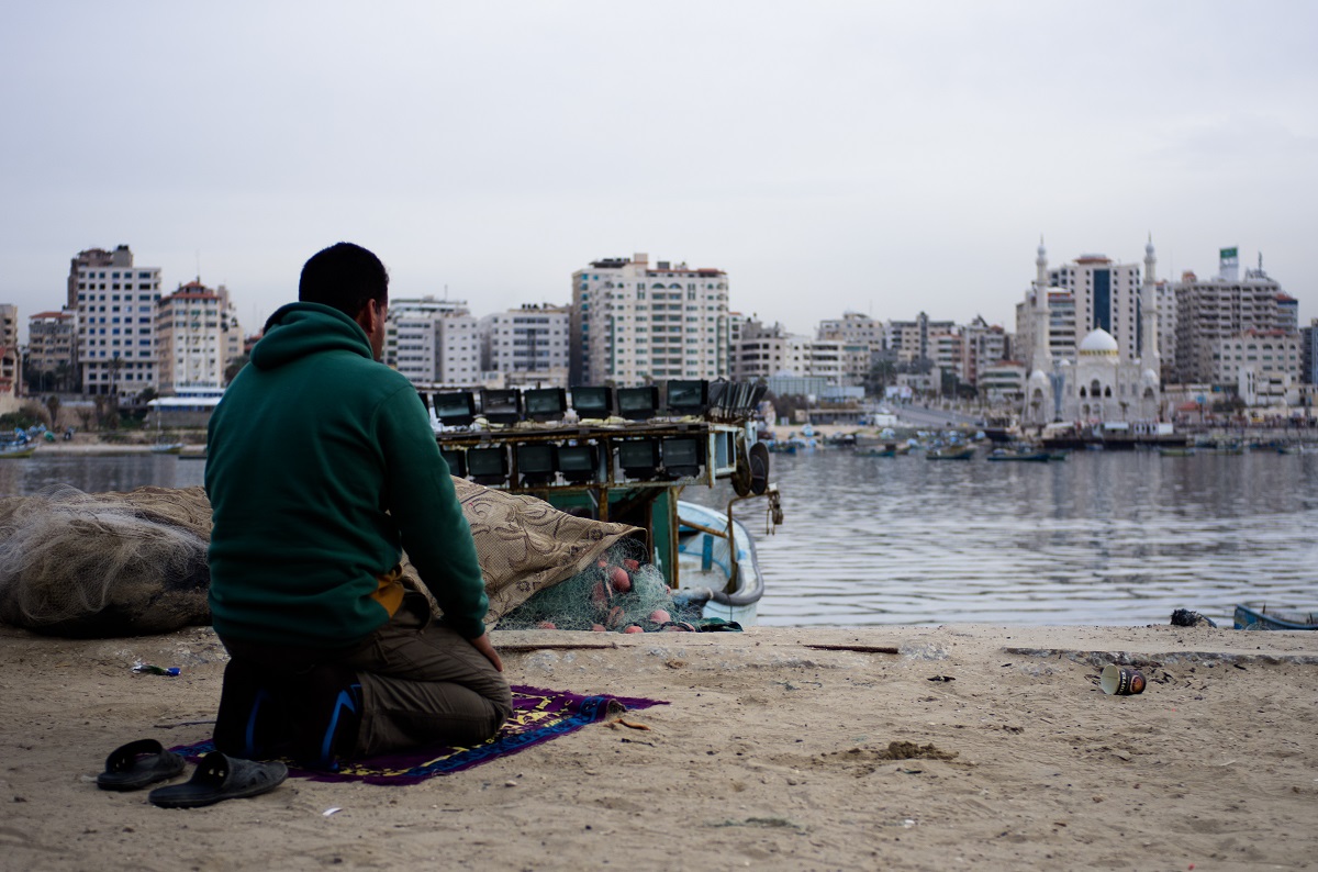 A Palestinian man prays at Gaza’s port, where the enclave’s crucial fishing industry now struggles. Photo by Kaamil Ahmed/Mongabay.