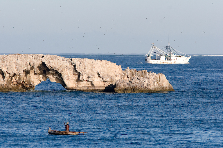 A traditional fisher keeps an eye on a shrimp trawler operating close to shore on Madagascar’s west coast. Photo by Garth Cripps.