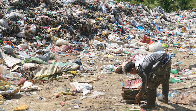 A scavenger collects reusable plastic from the illegal open dumpsite in Malapatan town in the southern Philippines. Image by Bong S. Sarmiento for Mongabay.