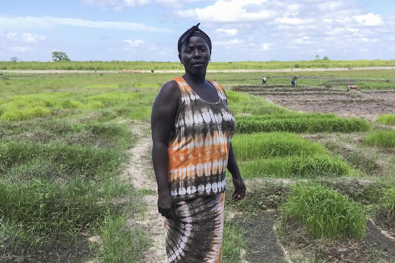 Souadou Sambou, a fishmonger, poses by the rice fields behind her home. Image by Jennifer O’Mahony for Mongabay.