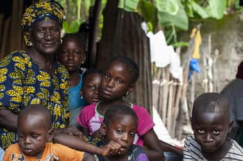 Dienaba Diedhiou, an oyster collector in her 70s, poses with her grandchildren. Image by Jennifer O’Mahony for Mongabay.