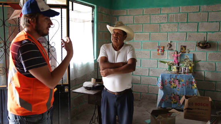 Javier Hernández, a member of ONergia, a solar power cooperative based in Puebla City, discusses home solar panel installations with a curious neighbor. Image by Ethan Bien for Mongabay.