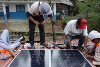 Members of the Tosepan cooperative’s youth solar panel installation team and the ONergia solar cooperative put the finishing touches on a domestic panel installation while community members chip in. Image by Ethan Bien for Mongabay.