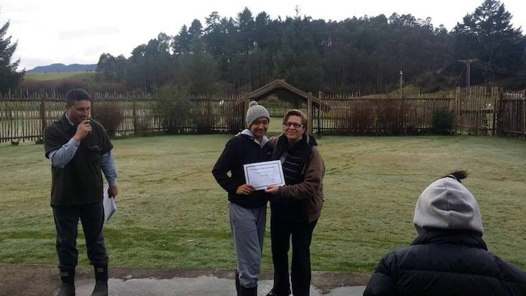 Brenda Tahi (right) and Puke Tīmoti (left) present a completion certificate to a Te Whare o Rehua forest academy participant.