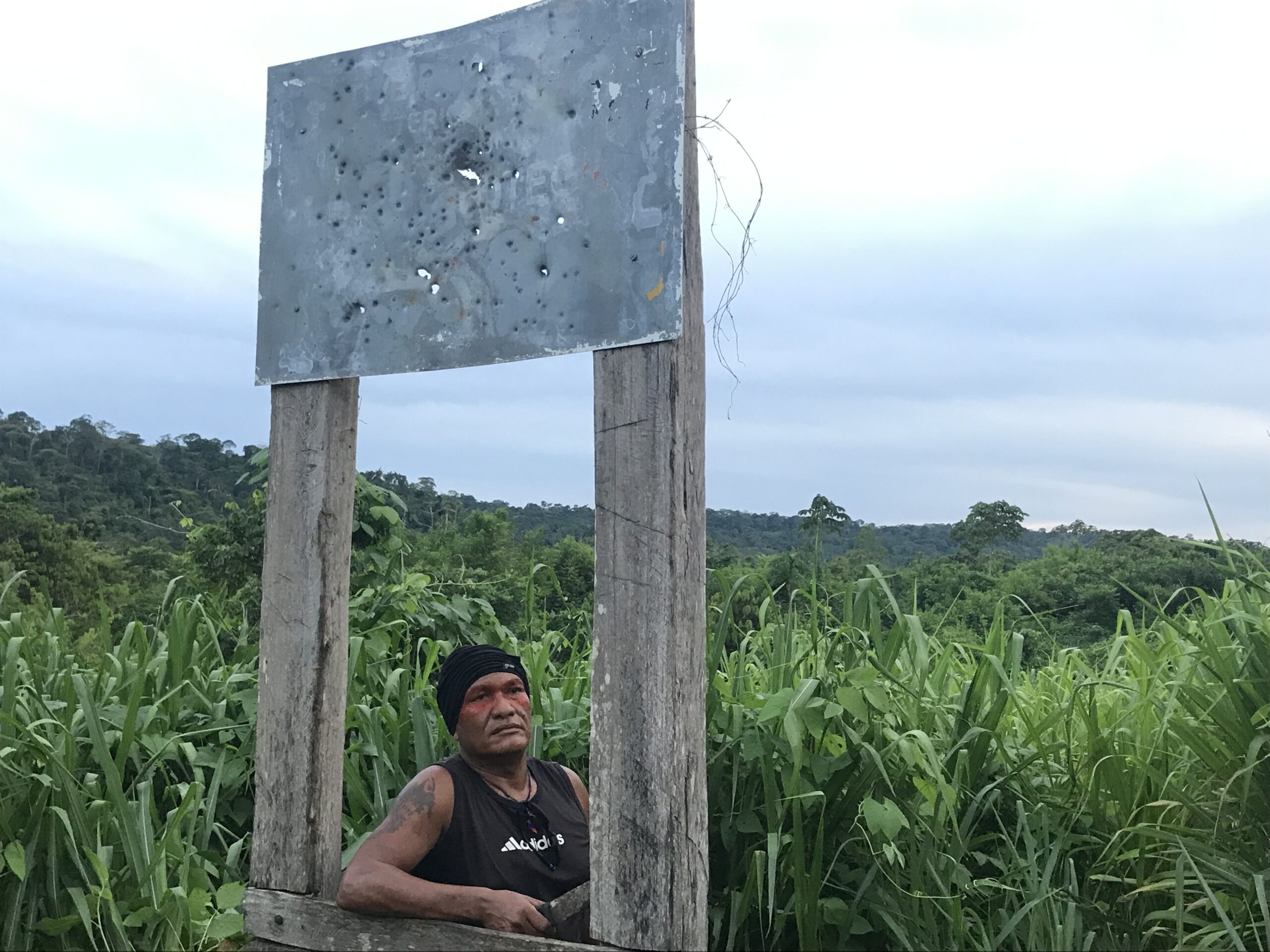 Olímpio Iwyramu Guajajara, the leader of the "Guardians of the Forest," poses for a photo in front of the Arariboia sign that is all engraved by bullet marks, in Maranhão state, on Jan 30, 2019. Image by Karla Mendes/Mongabay