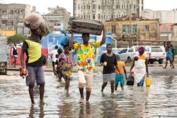 Beira residents carrying belongings wade through flooded street in Beira.