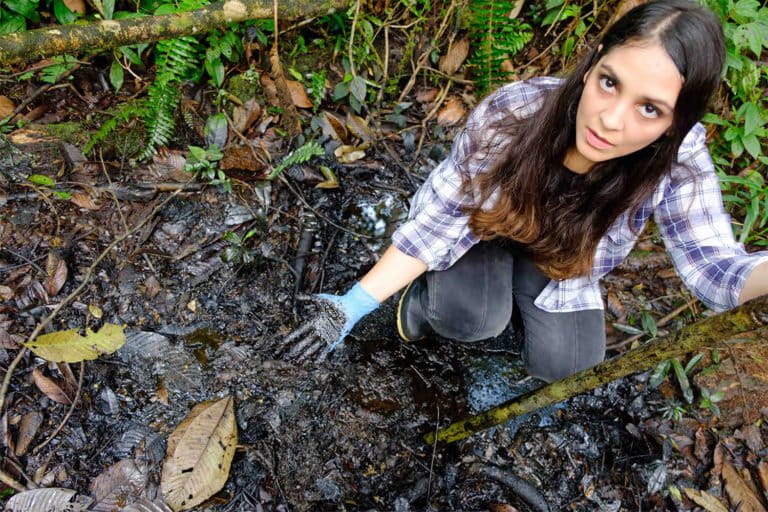 In the Pozo Aguarico region of Ecuador, lawyer Maria Cecilia Herrera shows the oil pollution that remains in the ground 30 years after oil production ceased. Photograph by Enrico Aviles, 2020.