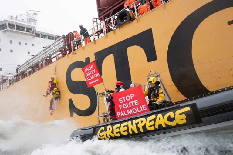 A team of climbers from Greenpeace Netherlands hang from the side of the 185m long Stolt Tenacity, preventing the gigantic palm oil tanker from mooring in Rotterdam harbour in 2018. Activists hold a banner reading reading: 'Stop Foute PalmOlie' (Drop Dirty Palm Oil in Dutch). The cargo ship is carrying palm oil products belonging to Wilmar. Photo © Marten van Dijl / Greenpeace