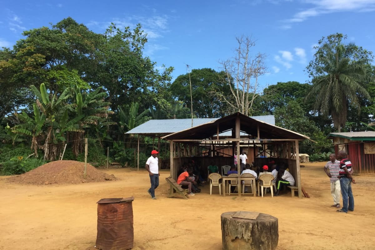 Men sitting under roofed shelter in the Gabonese village of Massaha. Image courtesy Graden Froese.