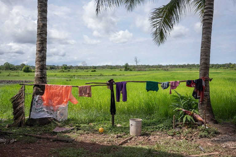 Clothes dry in front of a portion of Kheang Ra’s rice fields. While he waits to be issued a land title, he’s concerned that his land will be grabbed by powerful individuals. Image by Andy Ball.