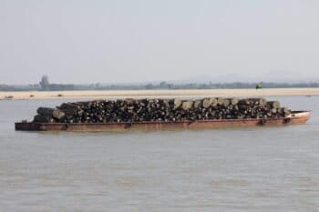 A barge transports teak logs