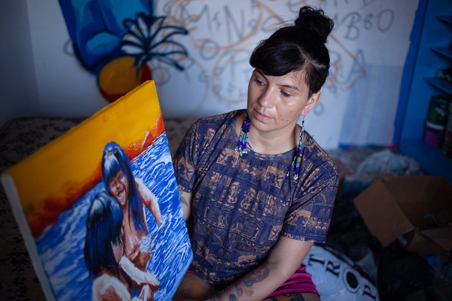 Chermie Ferreira, a graffiti artist from the Kokama Indigenous group, holds one of her paintings in her studio on the outskirts of Manaus. 