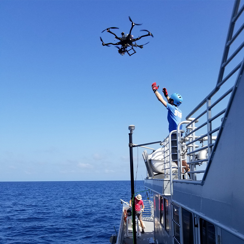 A marine researcher launching a drone for ocean color surveys