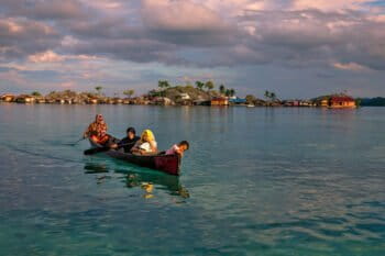 Bajo women canoeing from the village to a tourist beach.