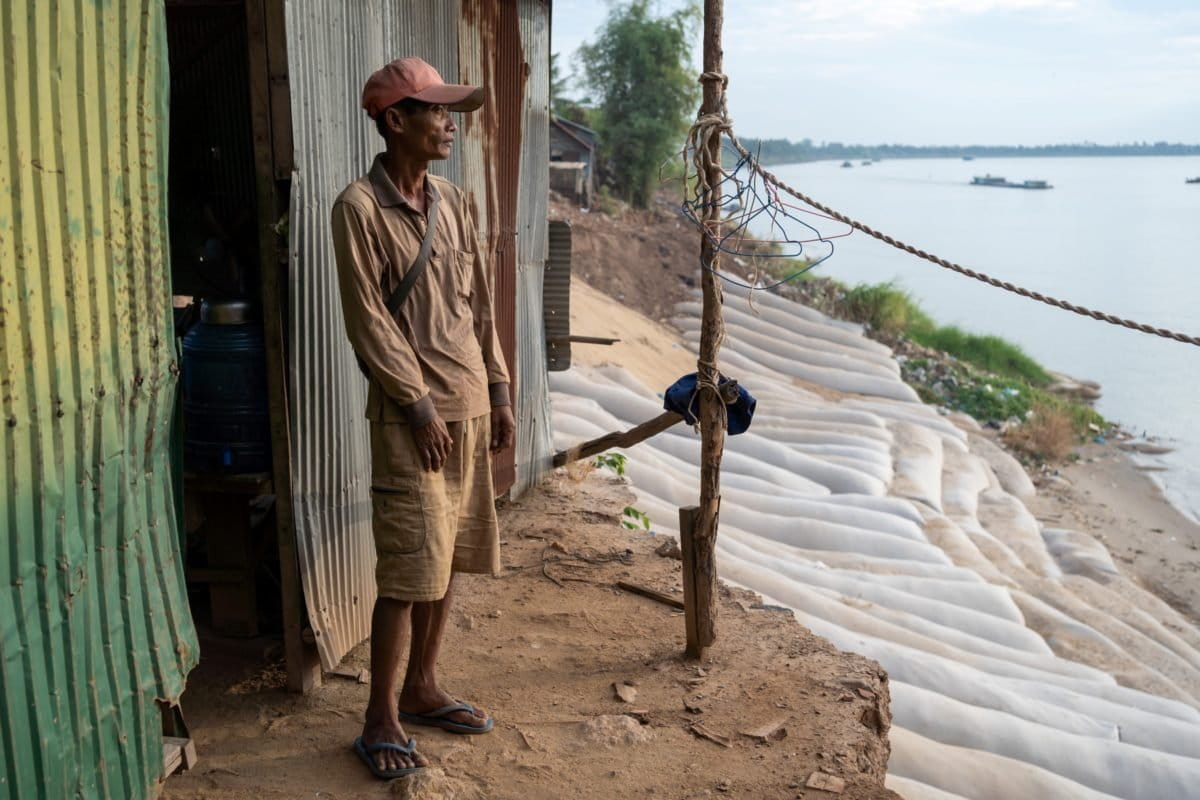 A Roka Koang resident looks out at the riverbank repairs behind his house.