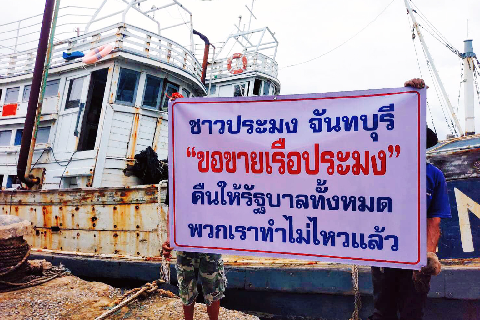 Docked commercial fishing vessels with signs stating, “We want to sell all our boats to the government. We can't stand it anymore"