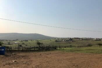 Wide shot of scattered buildings on green hills, a mountain on the horizon. Image by Victoria Schneider for Mongabay.