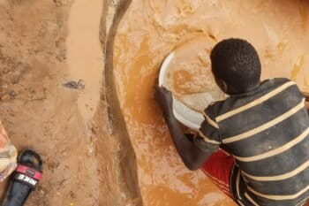 Saliou Hassana, a 17-year-old gold miner, extracting and collecting gold nuggets using mercury at Kambélé III. Image © Yannick Kenné.