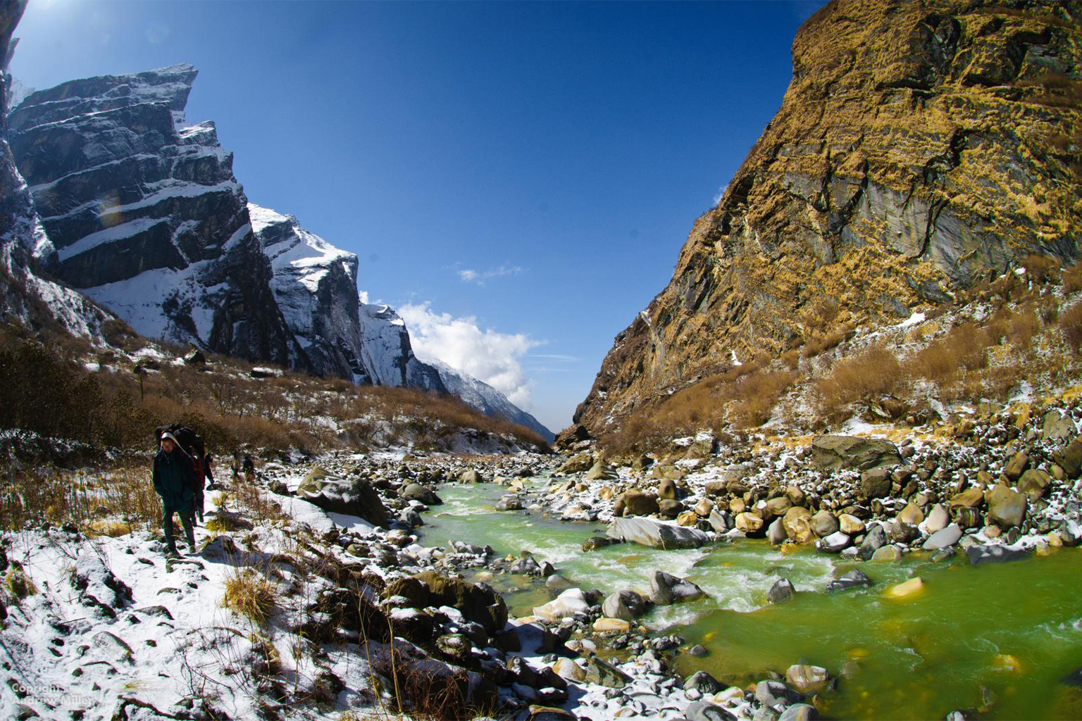 A man walks along a stream.