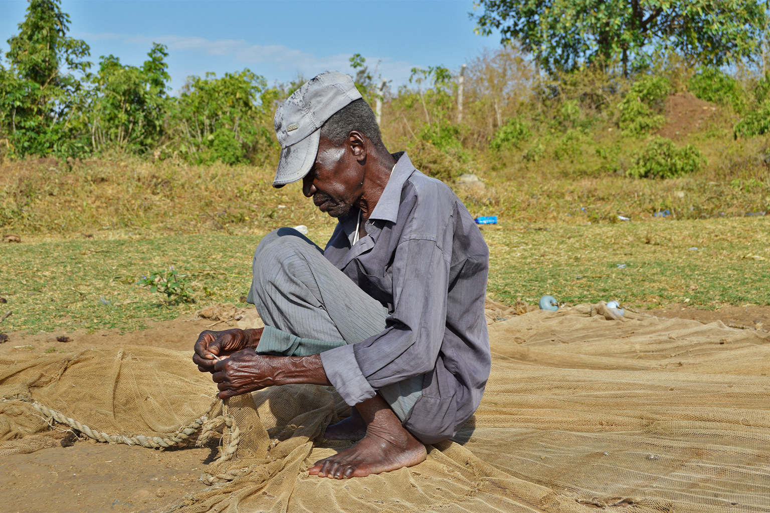 A fisher repairs his fishing net.