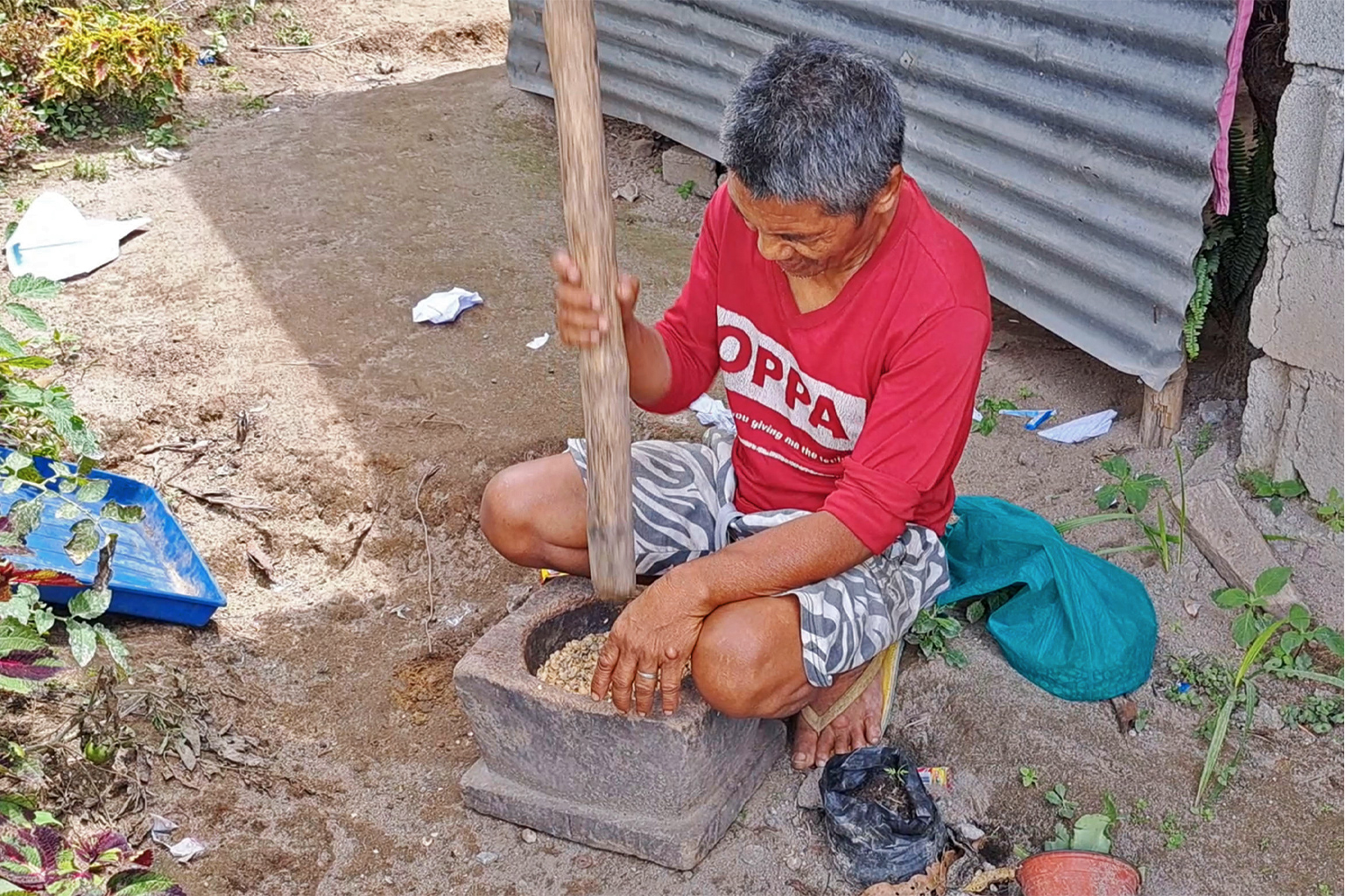 A villager pounds human-picked coffee beans to remove their pulp.