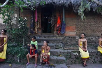 Women from a village in Bali in front of a house that preserves the traditional architecture with earthen wall on the front.