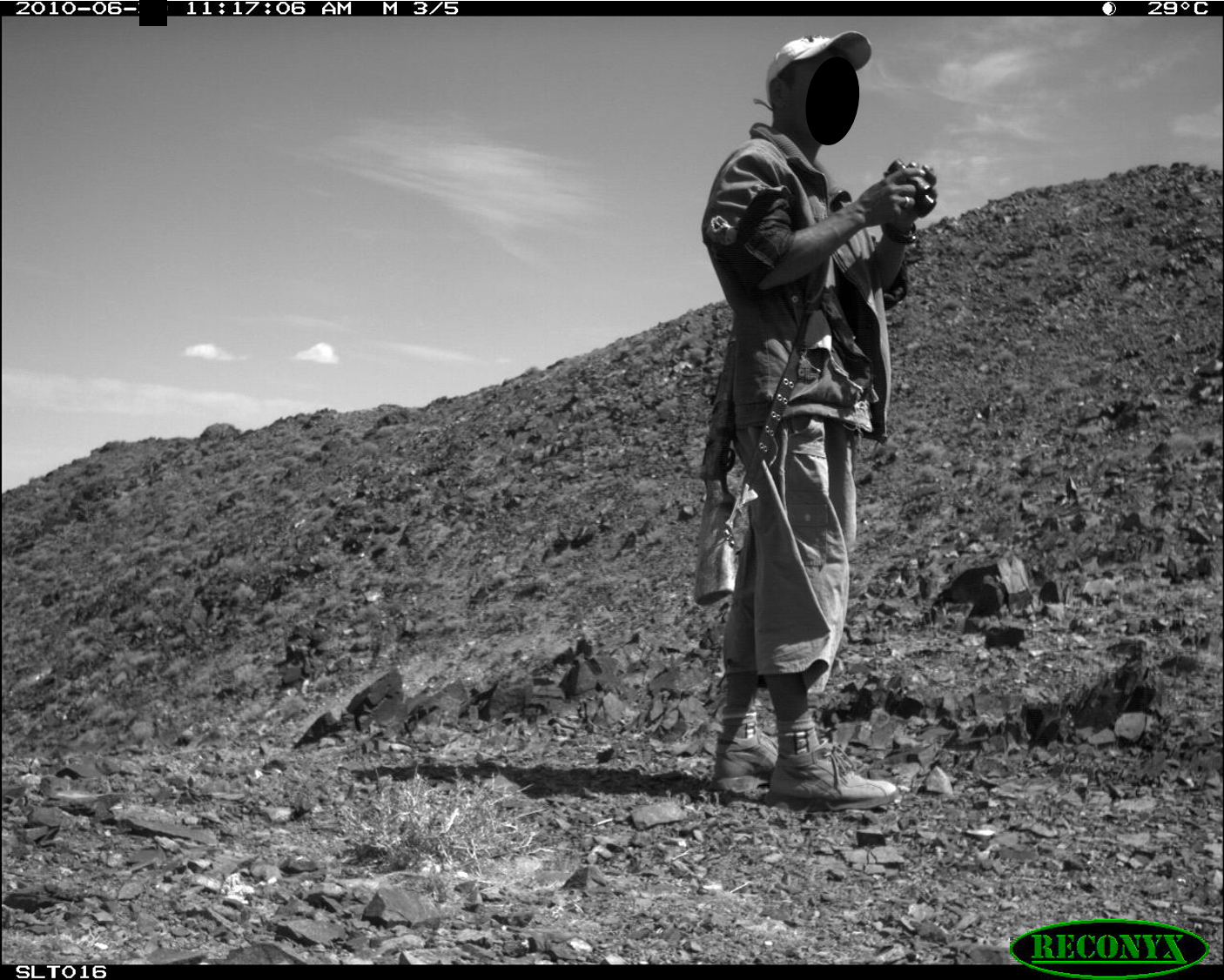 Image of a man with a gun captured by a camera trap. 