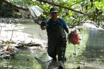 Volunteers clearing plastic trash gathered from river barriers. Image courtesy of Sam Benchegjib.