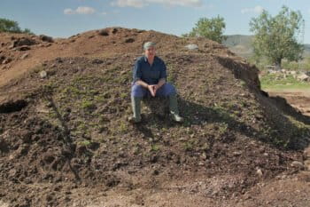 Santiaga Sánchez seated atop a pile of compost she calls her “brown gold.”