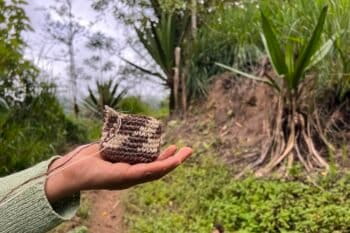 Silvia Vetancourt holds out a coin purse she is crocheting from cabuya fiber on the path to Plaza Gutierrez, Ecuador. Photo by Liz Kimbrough.
