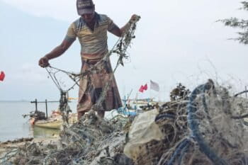 A fisherman cleans the plastic waste caught in his net.