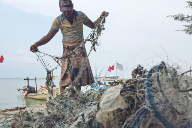 A fisherman cleans the plastic waste caught in his net.