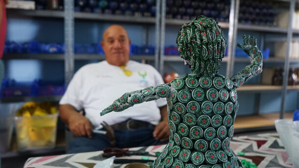 Green Phenix artist Erwin Sprot with one of his creations, a human figure made with beer crown caps.