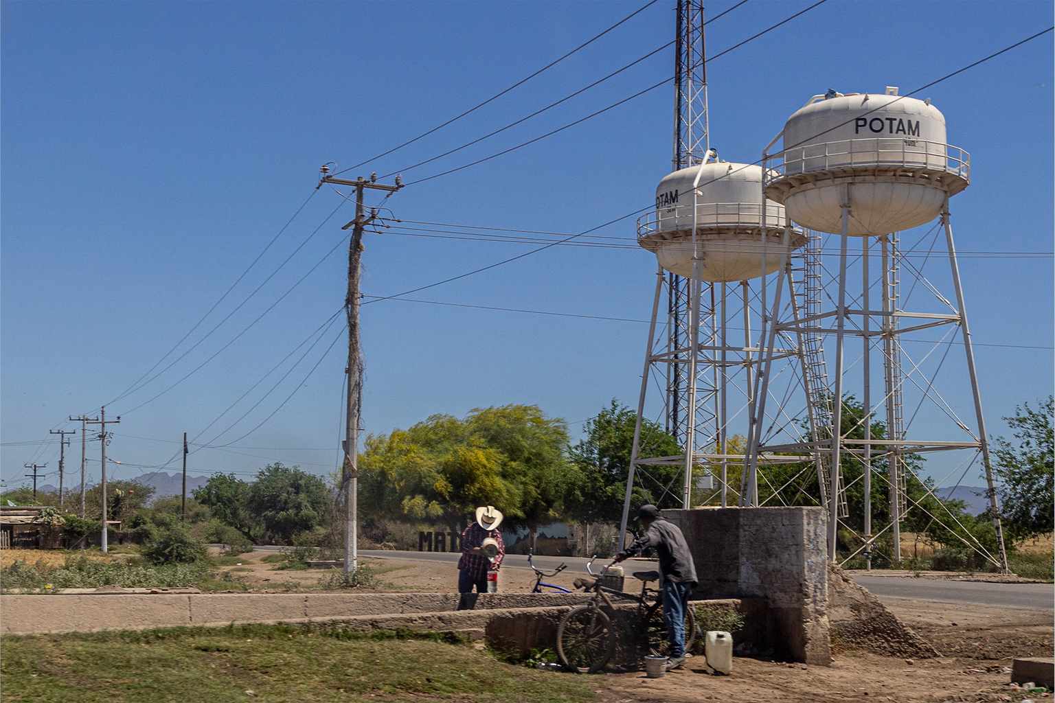 Yaqui community members pour water from a well into plastic bottles. 