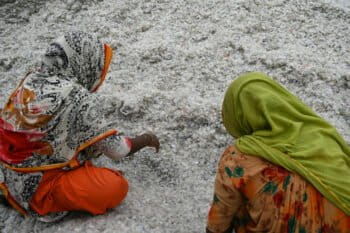 Two workers sift through plastic waste collected for recycling.