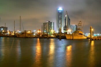 Corpus Christi at night, with fishing and pleasure boats set against the skyline. Image by Terry Ross via Wikimedia Commons.
