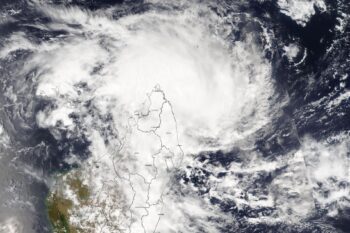 Banner image of Cyclone Dikeledi passing by northern Madagascar. Satellite image by NASA via Wikimedia Commons (Public domain).