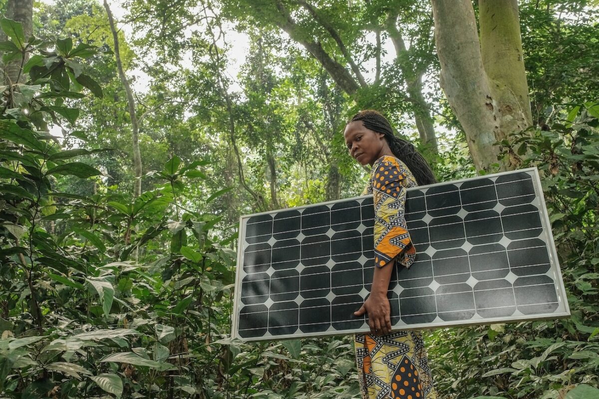 A woman carrying a solar panel in Yangambi, DRC. Image by Axel Fassio/CIFOR via Flickr (CC BY-NC-ND 2.0).