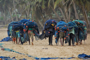 Fishers in Ghana carry their nets on the beach.