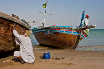 A fisherman repairs his boat on a beach in Soomar Goth, Karachi.