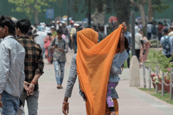 Banner image of a mother and a child protecting themselves from the heat during the 2024 heatwave in New Delhi. Image by Sanshey Biswas/In Old News via Flickr (CCBY2.0)