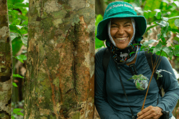 Woman standing next to a tree.