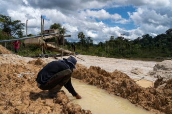Person kneeling in gold mine extraction site