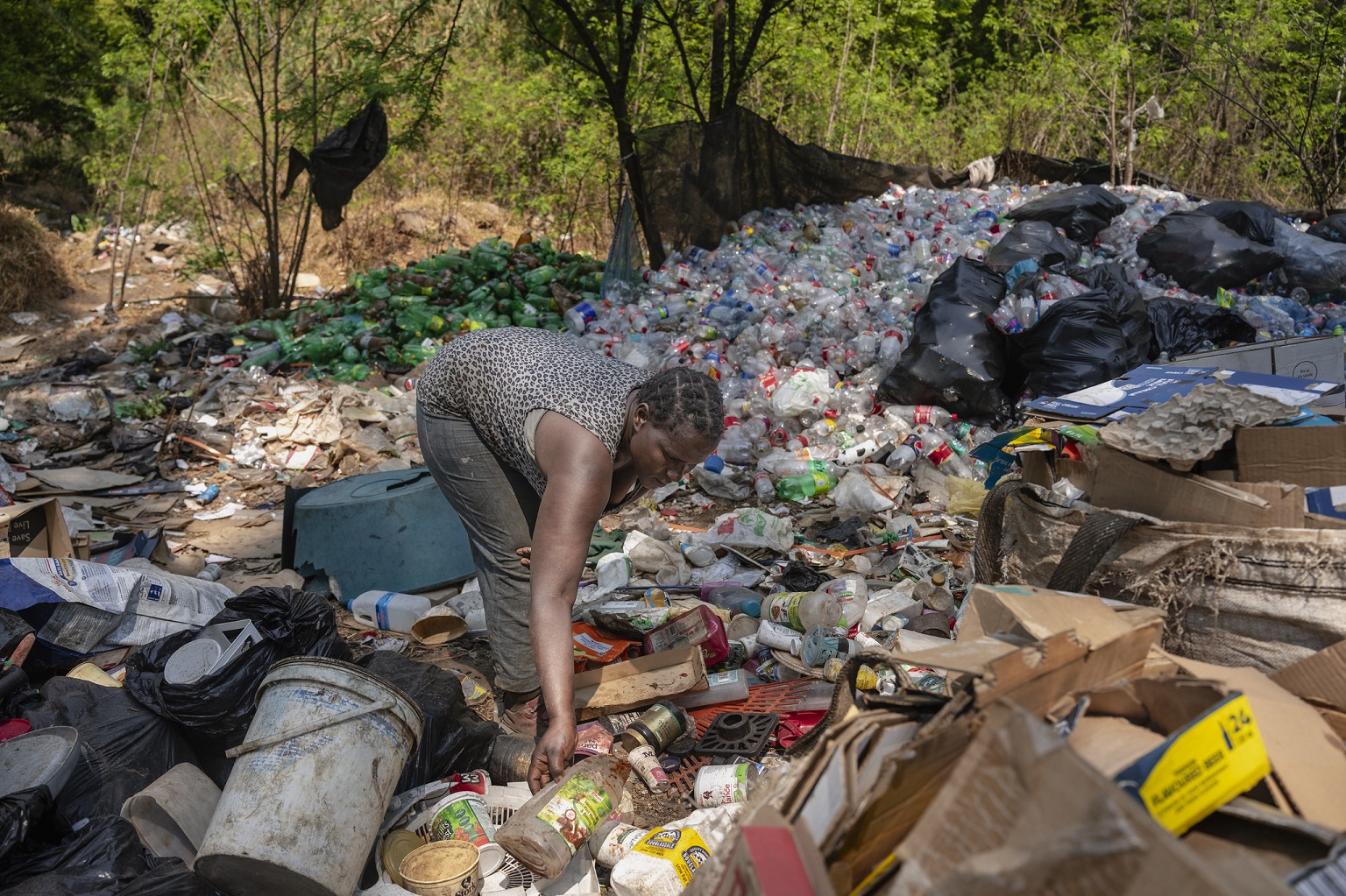 A woman collects plastic and other waste for recycling in South Africa. Less than 10% is recycled worldwide, with the rest remaining in the environment.